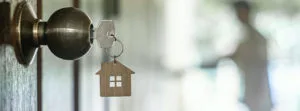 A key with a house-shaped keychain in a door lock, symbolizing homeownership and the excitement of securing a new home.